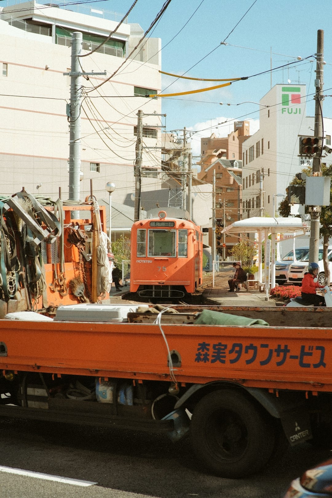 Orange flatbed truck on a busy street in Japan.